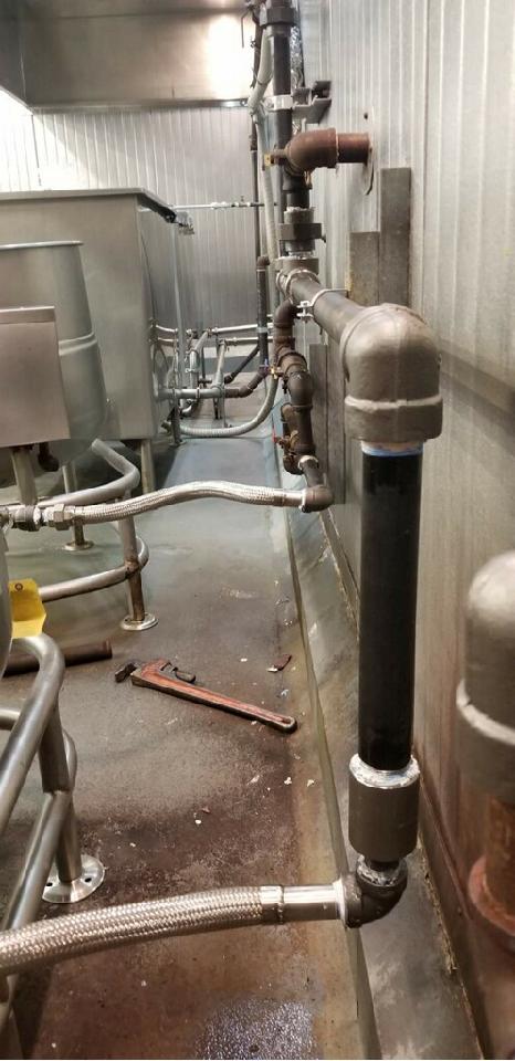 Black iron gas piping and flexible connectors serving commercial kitchen equipment