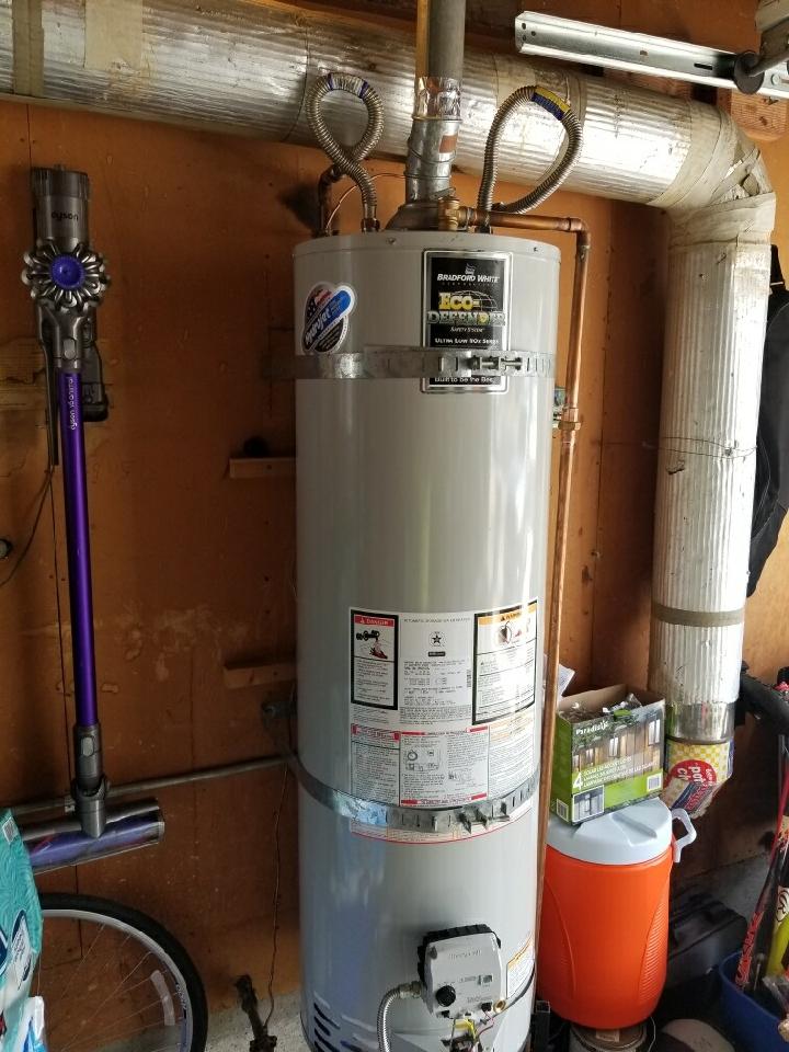 New residential gas water heater installed and seismically strapped in a garage