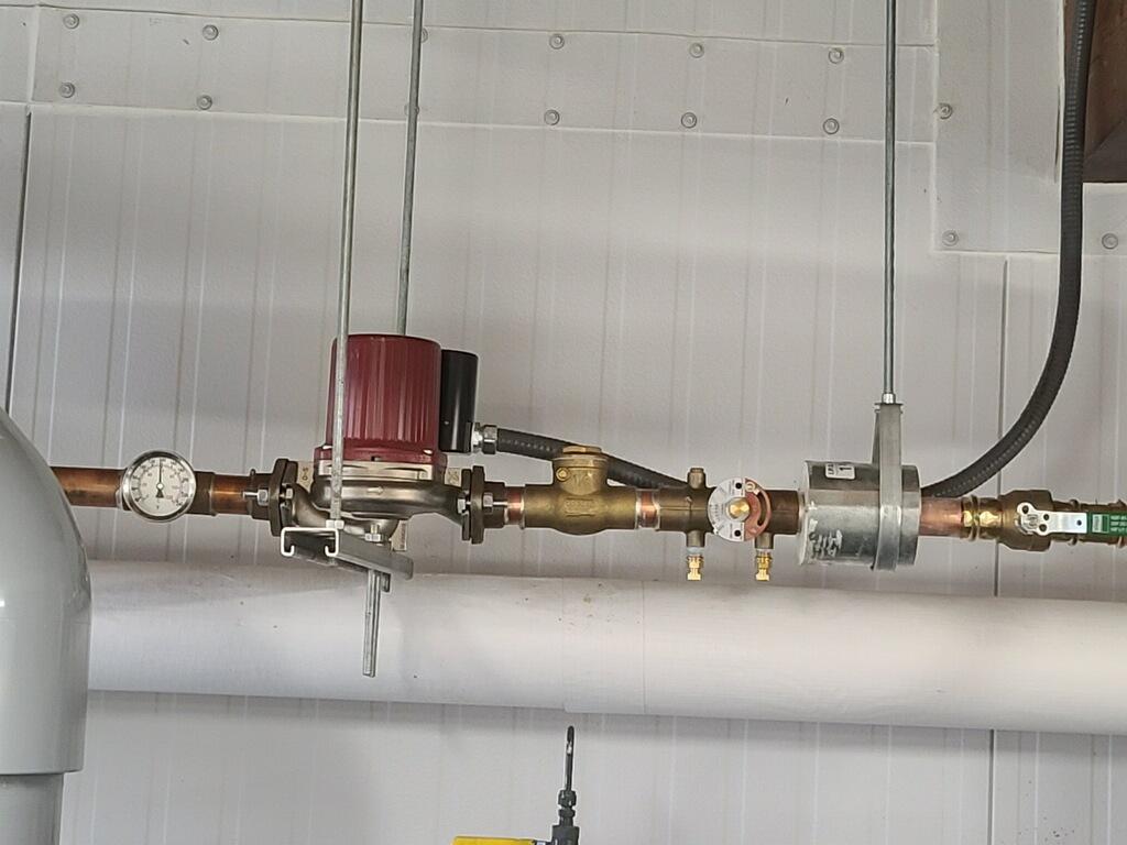 Hot water recirculation pump and pressure gauge on overhead copper lines in a commercial building