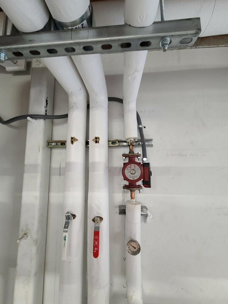 Insulated hot water piping with circulating pump and pressure gauge